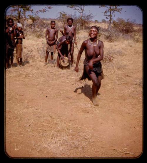 Woman dancing, people watching and clapping, and a boy playing a drum