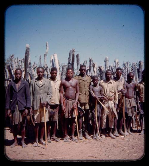 Group of men standing by a fence