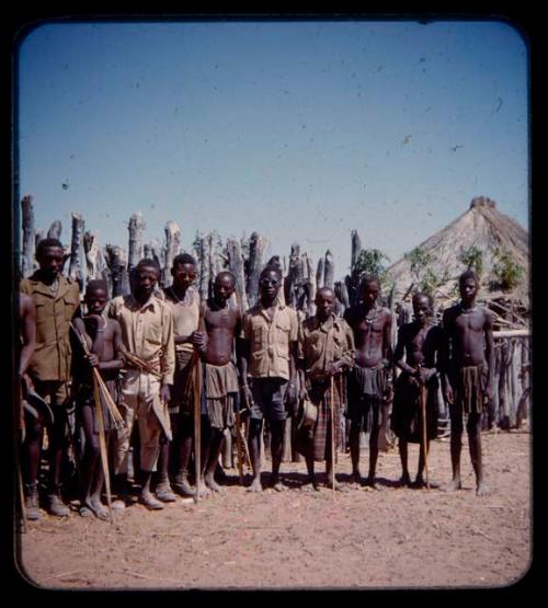 Group of men standing by a fence