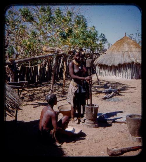 Woman pounding corn in a mortar with a large pestle