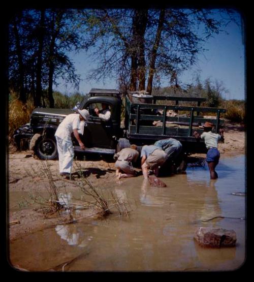 Expedition member pushing a truck stuck in a riverbank