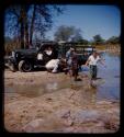 Expedition member pushing a truck stuck in a riverbank