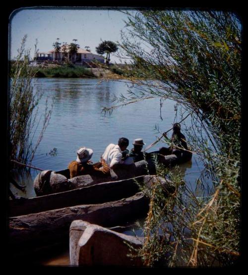 Expedition members in a canoe crossing a river