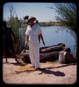 Senhor Simoes and another man standing on a riverbank, canoes behind them