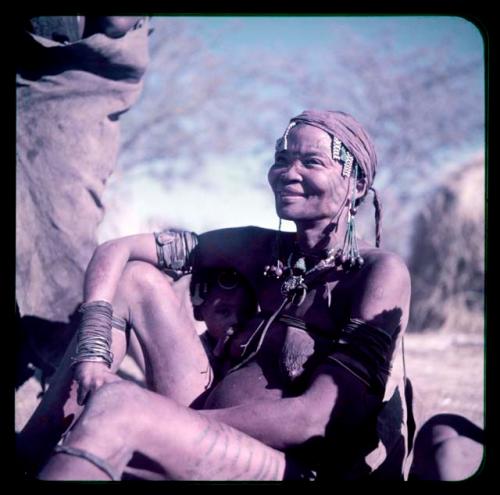 Children, Mother and children: Woman with scarification, wearing blue beads, sitting and nursing a child