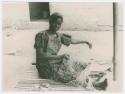 Woman sitting on the ground weaving