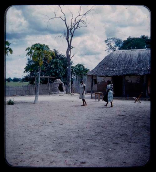 Two women standing in a yard by a house