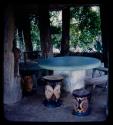 Round table and carved stools under trees