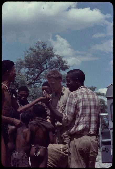 Men and boys standing with John Marshall in front of the expedition Land Rover