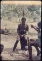 Man, possibly /Gunda, sitting, with two other people sitting next to him, "Qui Hunter" reclining in the background