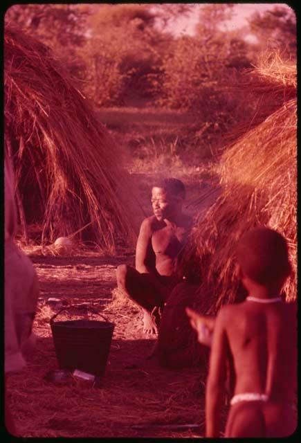 Man sitting next to a skerm, with a child standing nearby