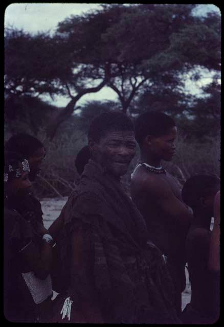 Man wearing a blanket around his shoulders, standing with a group of people