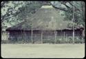 Large structure with a thatched roof, in a fenced enclosure