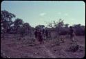 Group of people walking, with John Marshall carrying a tripod, view from behind