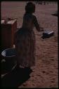 Woman wearing a dress, standing next to a metal basin