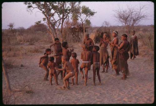 Women beginning to clap for a curing dance, children dancing