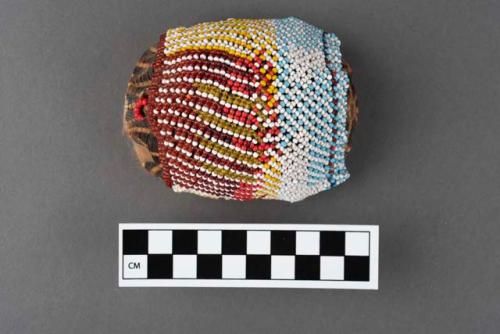 Tortoiseshell pouch in sleeve beaded with light blue, white, yellow, red, transparent red, transparent yellow and indigo blue beads in banded pattern; holds fragrant wood chips