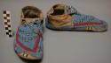 One pair of blue-beaded moccasins with yellow teepee and red-cross border motifs