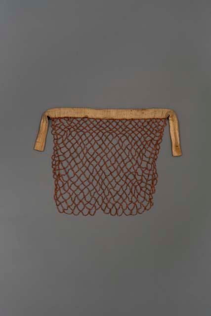 Openwork apron formed of strings of coral beads attached to a cloth band