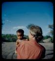 Expedition: Lorna Marshall holding a crying baby, over-shoulder view