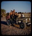 Expedition: Group of people wearing clothes gifted by the Marshall family, John Marshall, Ngani, and //Ao riding in Jeep