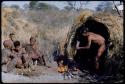 Food, Cooking: "/Qui Hunter" stirring food in a pot with a fire paddle, with his wife, /Naoka, her mother, "Old /Gasa," and an unidentified woman sitting near him