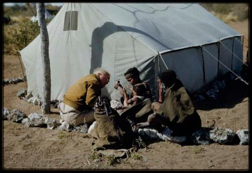 Expedition, Medicine: /Khoa ("/Qui Hunter's" daughter) in her mother's arms, having her burned leg treated by Laurence Marshall in front of a tent