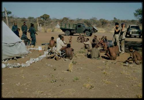 Expedition, Ethnographic work: People sitting in the expedition camp, with Lorna Marshall, Kernel Ledimo, Philip Hameva and other expedition members standing next to them