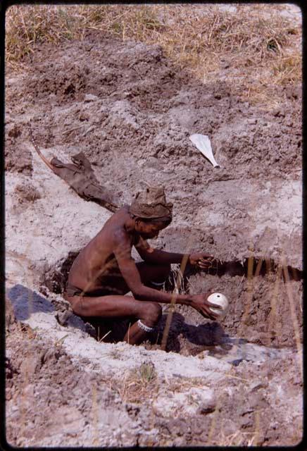 "/Gao Music" sitting at a waterhole and filling an ostrich eggshell