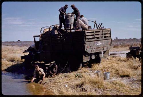 Expedition members pumping water into water drums in a truck