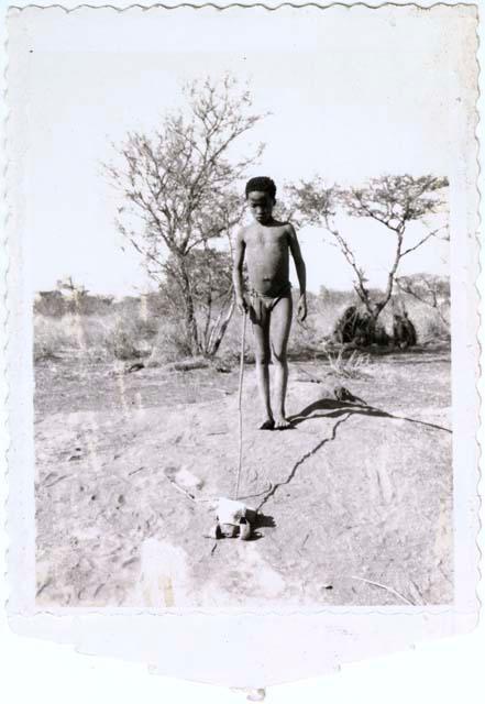 Boy pushing a toy car in front of a termite mound