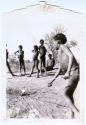 Boy pushing a toy car, with a group of boys watching him