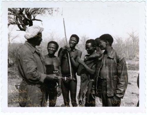 Group of men including ≠Toma, Debe (headman of Band 4), /Ti!kay and "/Gao Interpreter" standing with Frederick Geib, interpreter for the expedition