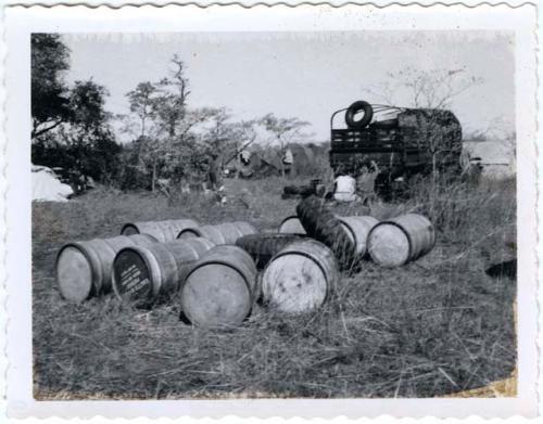 Large storage drums and tires, with expedition members next to a truck in the background