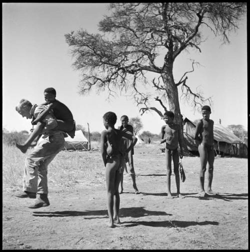 Group of boys playing with John Marshall, including /Gishay (son of "Old Gau") on his back, ≠Toma (son of Gau)  facing the camera, and !Naishi and //Ao (son of "Old ≠Toma" of Band 2) standing to the right