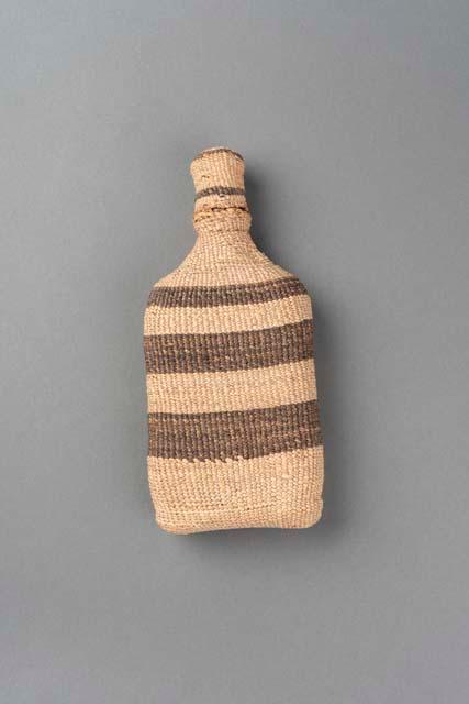 Bottle (A) completely covered in basketry twining with basketry lid (B)