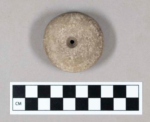 Ground stone discoidal, perforated in center.