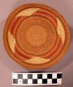 Basket, shallow bowl, woven grass, brown-orange & natural geom. design
