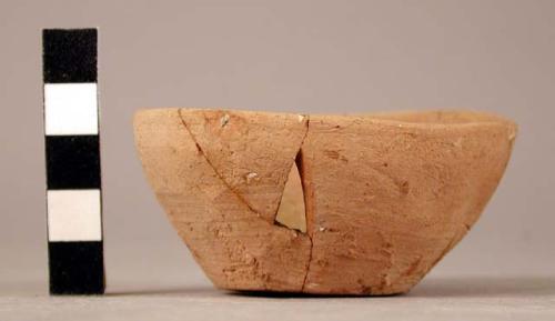 Ceramic bowl; reddish buff; flat base; mended; loss from body; chipped rim.