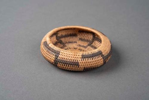 Miniature slightly oval coiled basket. natural with black geometric design.