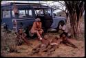 Group of young men sitting and lying down next to the expedition Land Rover, being interviewed by Nicholas England