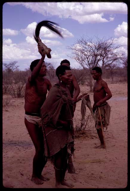 !Kxam dancing with an unidentified woman in a social dance, holding a wildebeest tail over her head