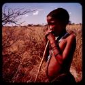 Boy standing, leaning on a digging stick to gather food