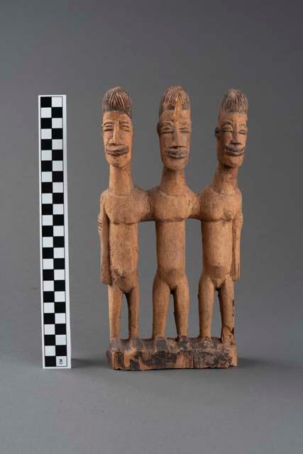 Carved and engraved wooden sculpture depicting three figures.