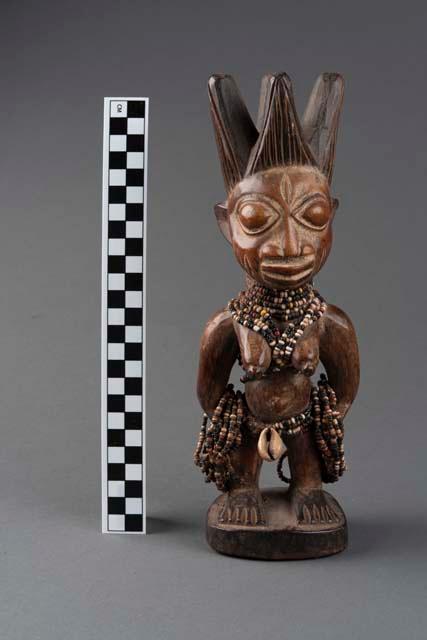 An engraved and carved sculpture depicting an Ibeji female figure