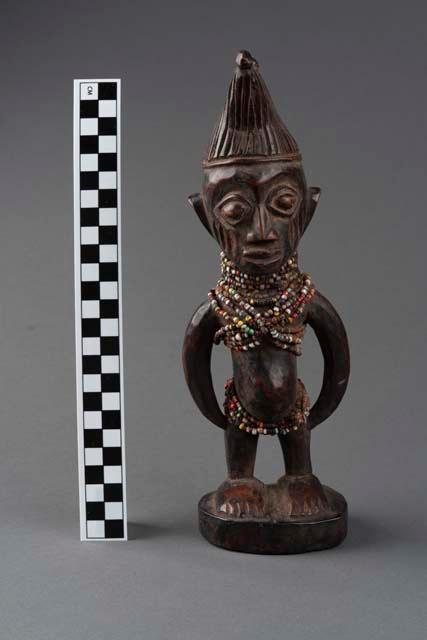 An engraved and carved sculpture depicting an Ibeji male figure