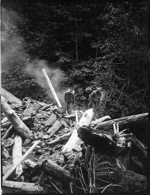 Men standing among logs near Godkin Creek