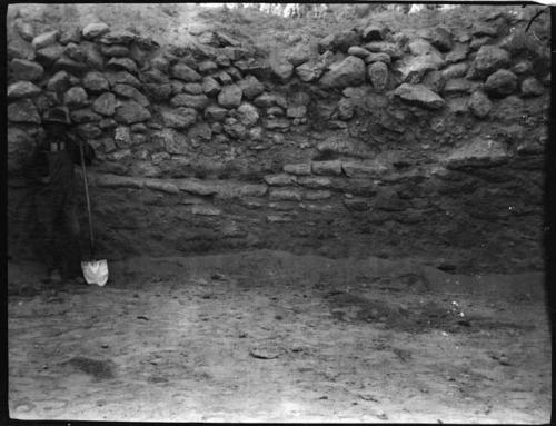 Man holding a shovel, standing in front of a rock wall