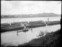 People sitting and standing on a canoe, with sugar boats behind them, in Nausori