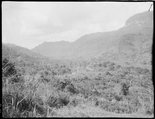 Houses in a valley, distant view, with mountains in the background